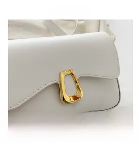 Detail of warm white shoulder bag with a gold geometric metal buckle and fine stitching