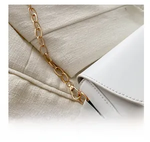 Close-up of golden metal chain hook and precise stitching on the white leather bag