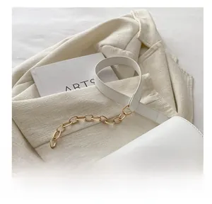 Detailed view of the white shoulder bag featuring a gold D-buckle and chain strap