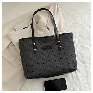 Overhead view of large tote bag with stripe bow pattern and black leather trim accents