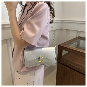 Fashionable silver metallic crossbody bag with gold buckle worn by model in a chic room