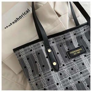 Detail of black lace tote bag with white stripes, polka dots and golden rivets
