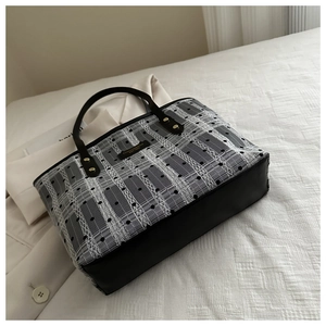 Close-up of black and white tote bag with lace mesh texture and fashion metal logo