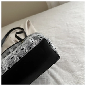 Close-up of lace embroidery and polka dot mesh details on a black and white tote bag
