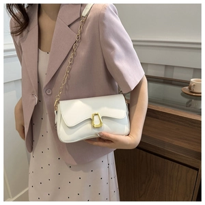 White shoulder bag with golden horseshoe buckle styled on model in soft indoor lighting