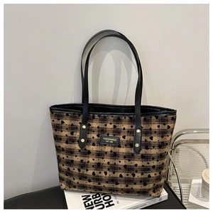 Close-up of black plaid tote bag featuring heart prints and a fashion logo patch