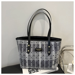 Detail of checkered tote bag featuring polka dots, leather straps, and metal rivets