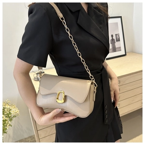 Close-up of beige shoulder bag with golden horseshoe buckle and chain strap detail