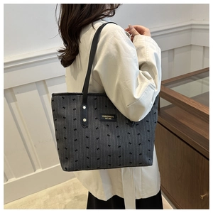 Detailed view of grey tote bag with black bow patterns and leather brand logo tag
