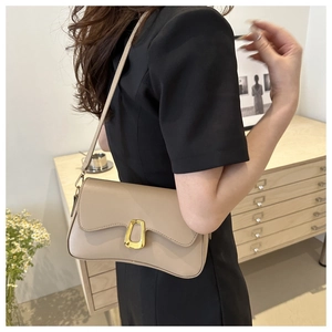 Detail of elegant beige underarm bag with gold horseshoe buckle on a model's shoulder