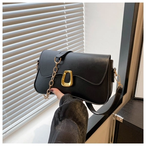 Detail of black crossbody bag with wave edge flap and gold trapezoid metal lock