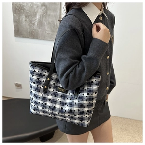 Detailed view of checkered tote bag with black heart prints and stylish leather handles