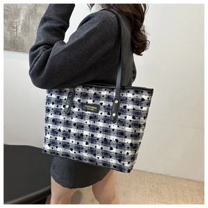 Close-up of blue and black plaid tote bag with heart print and fashion label detail