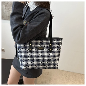 Close-up of a plaid tote bag with heart patterns and black leather logo patch detail
