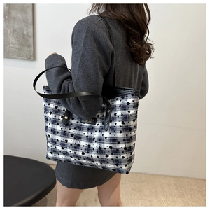Detail of blue and white checkered tote bag featuring black heart prints and metal rivets