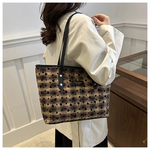 Detail of checkered tote bag featuring black heart patterns and leather brand patch