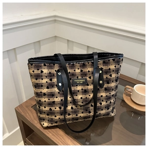 Detailed close-up of heart print tote bag with black handles on a glass table