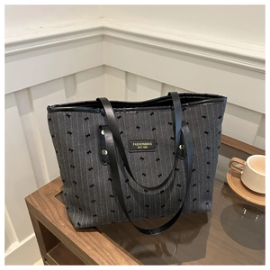 Detail of grey striped tote bag featuring black bow prints and metal fashion logo