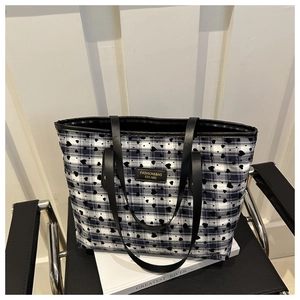 Detail of heart print tote bag with black leather handles and gold metal logo plaque