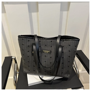 Detail of pinstripe tote bag with bow patterns and gold-stamped fashion label on black chair