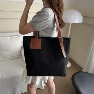 Minimalist black canvas tote bag with brown leather straps and large capacity for daily use