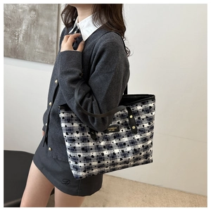 Detail of blue and white checkered tote bag with black heart prints and leather strap