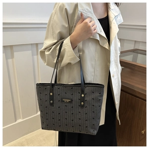 Detail of grey tote bag featuring black bow prints and a fashion brand label on the front
