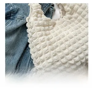 Gros plan détaillé de la texture popcorn blanc crème sur un sac à main plissé nuage