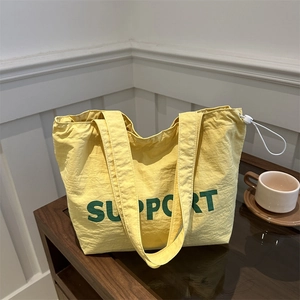 Sac fourre-tout en toile jaune avec texte Support vert sur une table en bois vintage