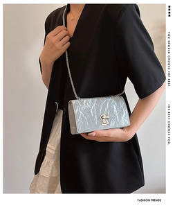 Detailed shot of pleated metallic texture and elegant chain strap on small square bag