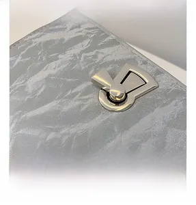 Macro shot of silver geometric lock detail on a gray marble textured small square bag
