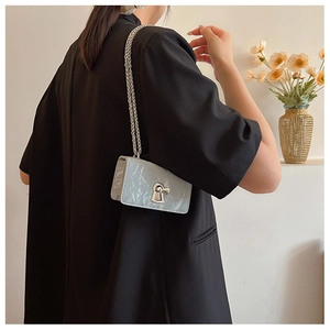 Detail of light blue wrinkled metallic shoulder bag with silver chain on model