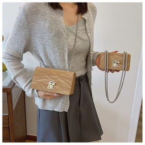 Close-up of khaki pleated leather crossbody bag with silver lock and chain strap
