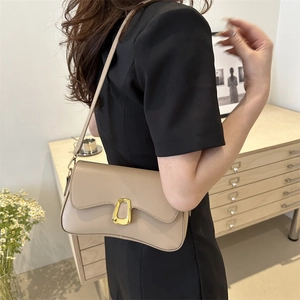 Chic beige leather underarm bag with gold ring buckle shown on a model shoulder
