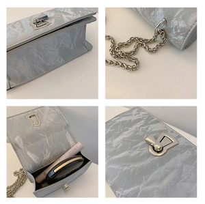 Detail view of silver textured square bag with metal clasp, chain strap and interior space