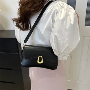 Minimalist black matte shoulder bag featuring an artistic gold buckle and adjustable strap