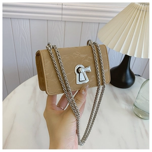 Detail of minimalist beige handbag with silver keyhole lock and marble texture