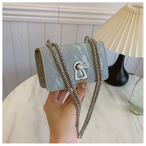 Detail of grey marble pattern faux leather handbag with silver keyhole lock and chain