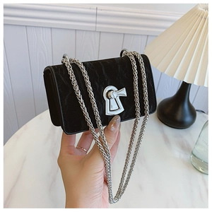 Detail of minimalist black handbag with silver chain and unique keyhole buckle closure
