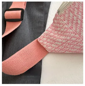 Détail de la bandoulière rose tissée avec boucle réglable sur sac à carreaux