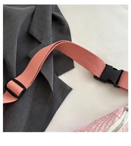 Gros plan sur la sangle tissée rose et la boucle en plastique noir de ce sac bandoulière