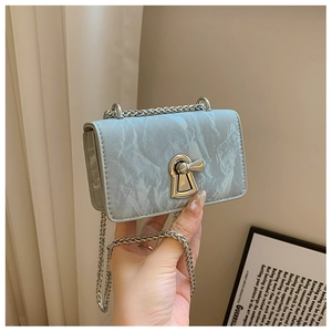 Close-up of textured light blue mini square bag with golden lock and chain strap detail
