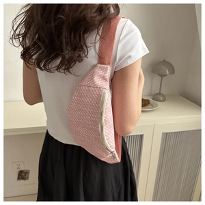 Détail de la texture tissée rose et blanche sur un sac banane avec fermeture éclair en métal
