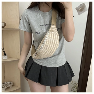 Détail d'un sac de poitrine en paille avec bandoulière en toile et zip argenté