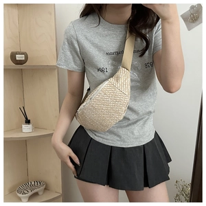 Détail d'un sac banane en paille tressée avec bandoulière large et fermeture éclair