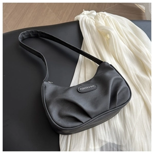 Detailed view of black pleated leather crescent bag with fashion label and shoulder strap