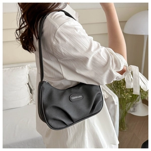 Detail of black pleated crescent bag featuring an oval leather tag and matte finish