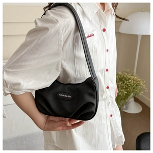 Close-up of black pleated hobo bag featuring a round logo patch on a shoulder strap