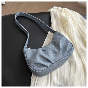 Detailed view of the pleated blue-grey crescent bag with silver zipper and logo tag