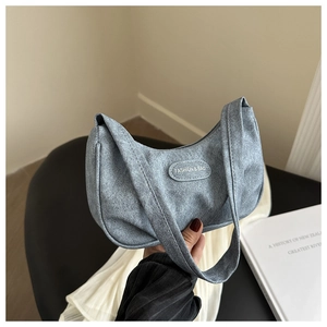 Detail of blue crescent shoulder bag featuring textured leather and embossed fashion label
